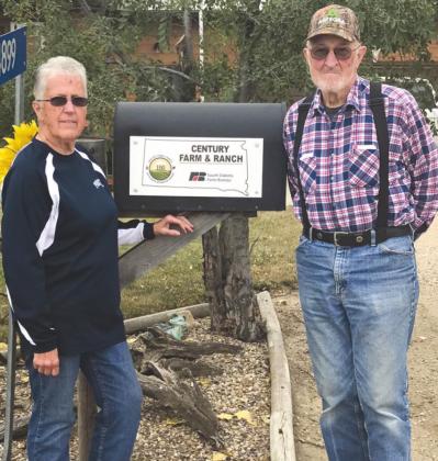 David and Sharon Bushnell stand next to their mailbox with the Century Farm &amp; Ranch plaque presented to them for the years of ownership of the Brammer Farm.