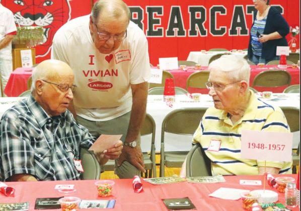 Members of the Vivian High School l-r: Lorne Smith, Tom Authier, and Darrel Lintvedt look at old photographs.