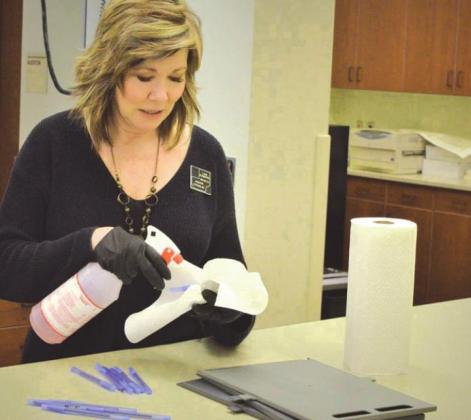 Meade County Auditor Lisa Schieffer disinfects voting equipment to keep people safe during a March 23 special election in Sturgis. Auditors across the state are making plans for a safe and secure 2020 general election whether ballots are cast by mail or in person. Photo: Courtesy Rapid City Journal