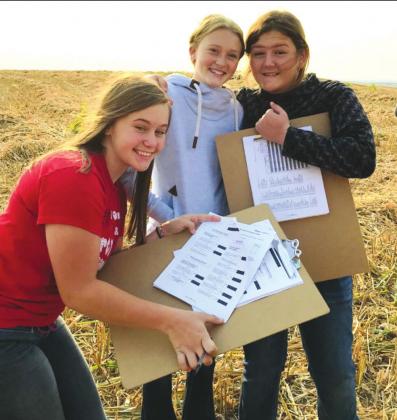 Freshmen Morgan Schelske, Skyler Volmer, and Texi Garnos show off their sheets on Tuesday at the Land and Range Judging contest.